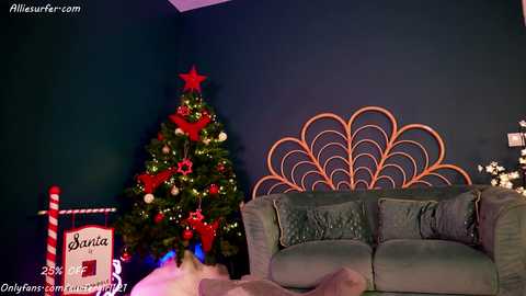 Media: Video of a festive living room with a decorated Christmas tree, a teal couch, and a large, ornate, wooden headboard.