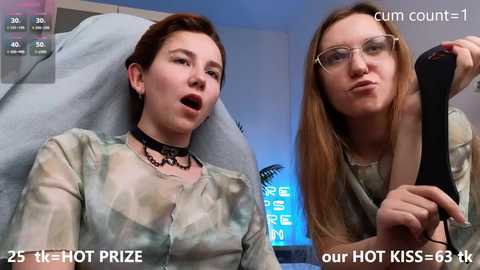 Media: Video of two young women, one wearing camo, the other a black choker, both making suggestive faces in a dimly-lit room. Text overlays indicate 25,000+ views and 65,000+ likes.