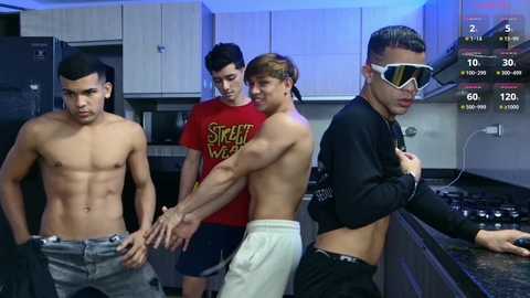 Media: Video of four shirtless young men in a modern kitchen, one wearing a black hoodie, two wearing colorful t-shirts, and another with a white headband and sunglasses.