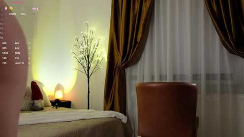 Media: A video of a cozy bedroom with a bed, a tall, slender lamp, and sheer white curtains with golden-brown drapes.