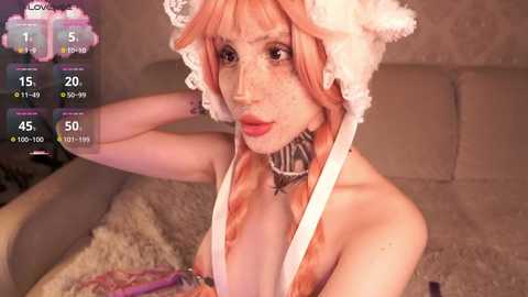 Media: Video of a pale-skinned woman with freckles, wearing a white fluffy hat and a choker, posing topless on a beige couch.