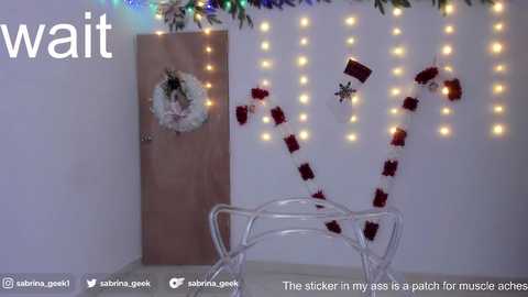 Media: Video of a festive Christmas scene with a wooden door adorned with a wreath, white string lights, and red-and-white striped candy canes on a white sled.