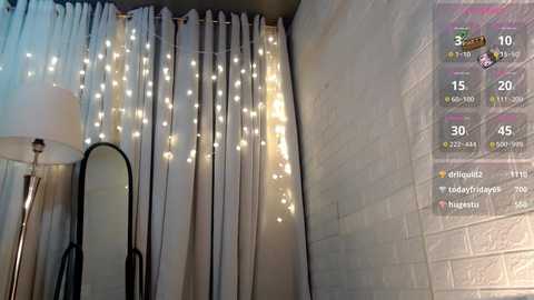 Media: A video of a cozy bedroom with a white brick wall, a tall mirror, a lamp, and a curtain adorned with fairy lights. A digital overlay shows game stats on the right.