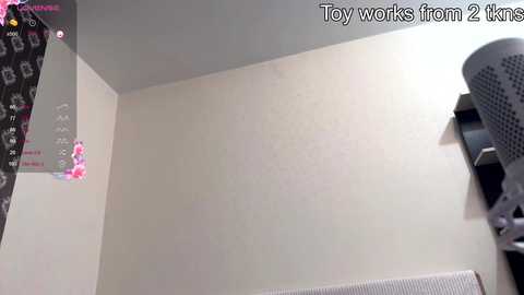 Media: Video of a beige wall in a room, featuring a pink toy robot on the left and a gray fan on the right, with text at the top reading \"Toy works from 2 km.\