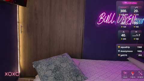 Media: A video of a bedroom with a bed covered in a blue quilt, featuring a \"Bullshit\" TV show on the wall and a \"XOXO\" sign in the corner.