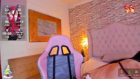 Media: Video of a cozy bedroom with a pink gaming chair, beige upholstered bed, stone accent wall, wooden nightstand, and a warm, dimly lit atmosphere.