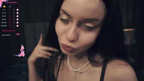 Media: A close-up video of a pale-skinned, dark-haired woman with heavy makeup, including eyeliner, pouting with a cigarette in her hand. Background is blurred, showing a dimly lit room with a \"Loverboy\" logo.