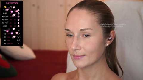 Media: A video of a fair-skinned woman with straight brown hair, wearing a white shirt, sitting against a wooden wall. A digital overlay shows a list of her followers.