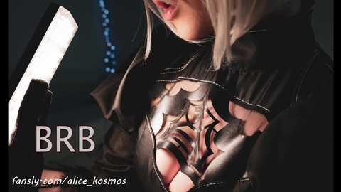 Media: A video of a woman with short blonde hair in a dark, shiny leather jacket featuring a detailed, metallic breastplate design. She's holding a camera with a bright light, focusing on the jacket's intricate patterns. The background is dimly lit.