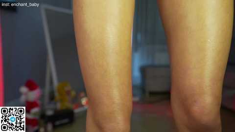 Media: A video of a pair of light-skinned legs, likely female, in a dimly lit room with a blurred background featuring festive decorations, including a Santa Claus figure.