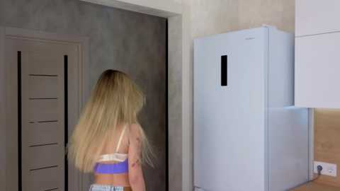 Media: A video of a blonde woman in a blue and white striped top, standing in a modern kitchen with a white refrigerator and beige walls.