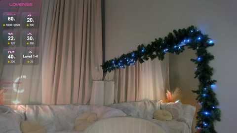 Media: Video of a cozy, festive living room with a large, mirrored TV screen displaying weather information. The room features a white sofa adorned with a green, blue-lit Christmas garland, and beige curtains.