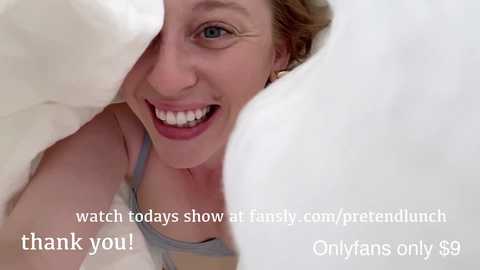 Media: Video of a smiling woman with light skin and blonde hair, partially covered by a white blanket, wearing a gray top. Text overlays invite viewers to watch a family meal and support OnlyFans.