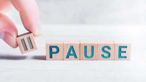 Media: Video of a hand holding a wooden letter \"P\" with a turquoise background, stacking it onto a wooden block spelling \"PAUSE.\" The background is a blurred, light gray textured surface.