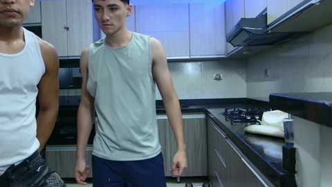 Media: Video of two young men in a modern kitchen. One wears a white tank top, the other a light gray sleeveless shirt.