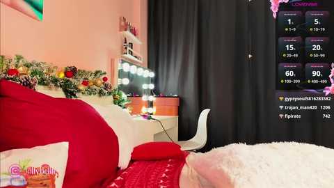 Media: A video of a cozy, festive bedroom with a white bed adorned with red pillows, a Christmas tree, and a fluffy white blanket. A vanity table with a mirror and a chair is visible in the background.