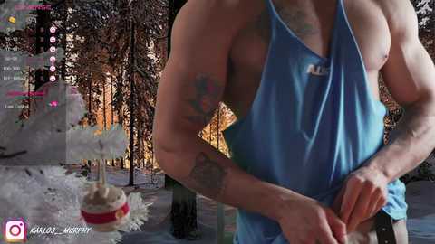 Media: Video of a muscular man in a blue tank top, standing in a snowy forest, holding a cupcake. Background shows a virtual reality gaming interface.