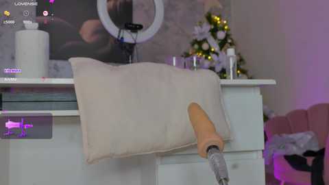 Media: Video of a cozy living room with a white throw pillow on a white couch, a ring light, and a Christmas tree in the background.