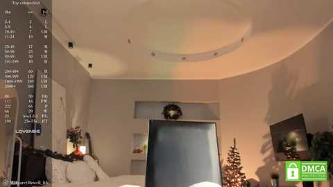 Media: A video of a cozy, modern living room with a large flat-screen TV, a Christmas tree, and a fireplace. The room is warmly lit, featuring beige walls and a minimalist decor.