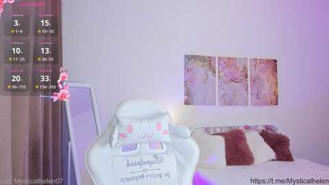 Media: A video of a minimalist, pastel-toned bedroom with a white chair, a bed adorned with plush pillows, and a pink flower arrangement. A digital clock displays the time.