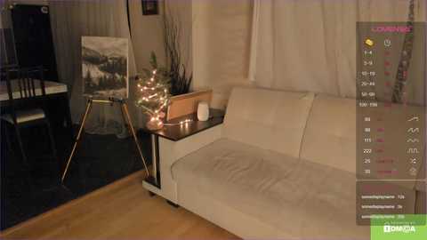 Media: A video of a cozy living room with a cream sofa, wooden floor, and a wooden side table adorned with a lit Christmas tree.