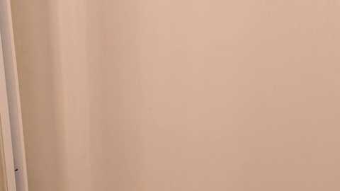 Media: A video of a plain beige wall with a slight shadow on the left side, possibly from a door or window frame. The image is simple and minimalistic, focusing solely on the wall's texture and color.