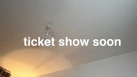 Media: A video of a ceiling with a white chandelier emitting a soft, warm light, and the text \"ticket show soon\" overlaid in white.