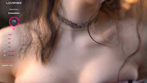 Media: A close-up video of a woman with fair skin, wet hair, and a black choker, taken from a low angle, showing her neck and cleavage.