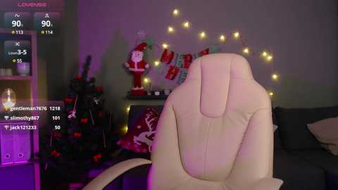 Media: Video of a beige gaming chair in a cozy, dimly lit living room adorned with Christmas decorations, including a small tree and a string of warm yellow lights.