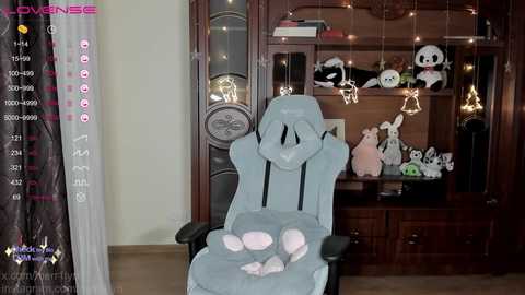 Media: A video of a child in a light blue recliner chair, surrounded by plush toys, including a panda and a bear, in a warmly lit room with wooden shelves and string lights.