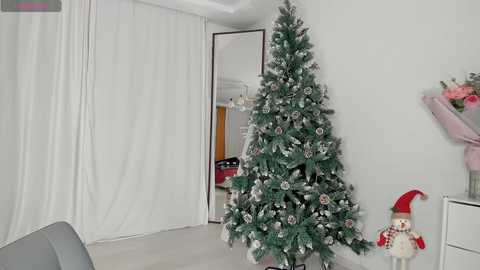 Media: A video of a minimalist living room with a decorated Christmas tree, a Santa figurine, and white curtains.