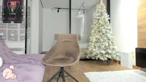 Media: A video of a modern living room with a plush lavender couch, a beige recliner chair, a tall Christmas tree decorated with white lights and ornaments, and a sleek black TV stand.