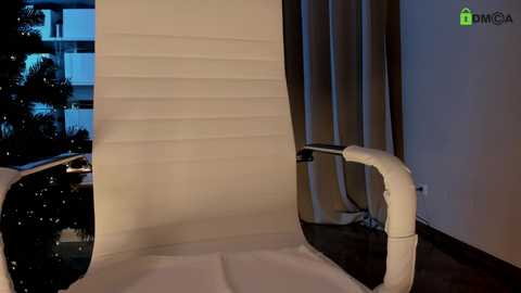 Media: Video of a sleek, modern white leather office chair with adjustable armrests, positioned in a dimly lit room with dark curtains and a window showing city lights in the background.