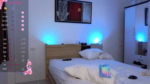 Media: A video of a modern, dimly-lit bedroom with a wooden bed, white pillows, a colorful rainbow-striped blanket, and blue ambient lighting.