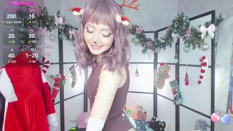 Media: A young woman with wavy, lavender hair and a Santa hat, dressed in a brown sleeveless top, stands in a festive, dimly-lit room adorned with Christmas decorations, including a red Santa coat and a plush teddy bear.