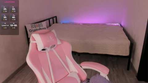 Video of a pink gaming chair with \"Kotobuki\" logo, facing a beige bed with purple LED strip lights in a minimalist room.