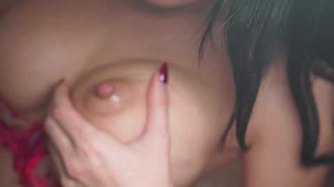 Media: Video of a close-up of a woman with light skin, dark hair, and red fingernails, partially covering her large, natural breasts with her hands.