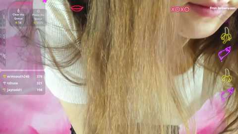 Media: A close-up video of a woman's face and hair, with pink overlay and digital stickers. She has light brown hair and is wearing a white shirt.