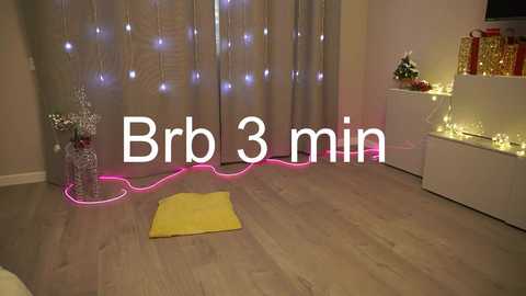 Video of a minimalist room with light wood floor, gray curtains, pink fairy lights, white shelves, and a yellow yoga mat. Text overlays \"Bro 3 min\" in white.