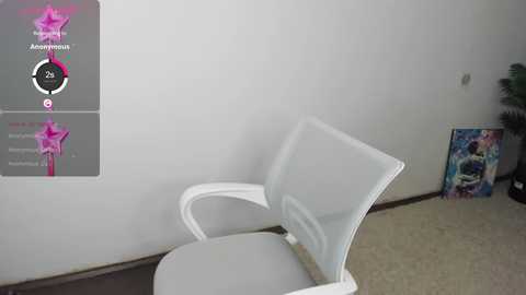 Media: Video of a white mesh office chair in a minimalist room with a grey wall, a potted plant, and a colorful poster on the right.