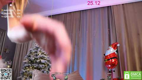 Video of a person in a Santa hat, blurred in motion, in front of a festive Christmas tree and a large, red and white Santa balloon. Background includes curtains and a DMC logo.