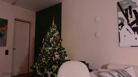 Media: A video of a modern, cozy living room with a lit Christmas tree, white walls, abstract art, and a white couch.