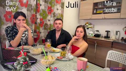 Media: Video of a lively, modern kitchen setting featuring three people seated at a table adorned with festive decorations and food.