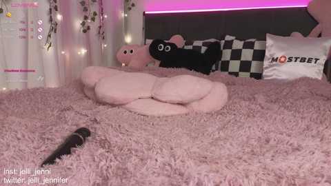 Media: Video of a cozy bedroom with a plush pink bedspread, stuffed animal figures, and a microphone on the floor.