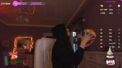 Media: Video of a woman in a black hoodie playing an arcade game in a dimly lit room with a chandelier, vintage decor, and a colorful cake in the background.