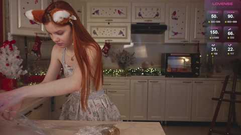 Media: Video of a young redhead woman in a festive kitchen, wearing a Santa hat, mixing cookie dough.