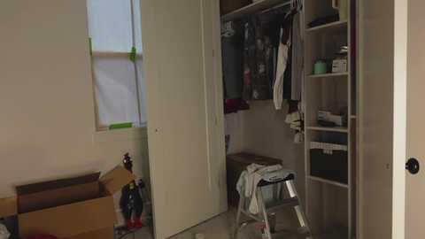 Media: Video of a cluttered, partially renovated room with white walls, open closet, green painter's tape, tools, and various construction materials.