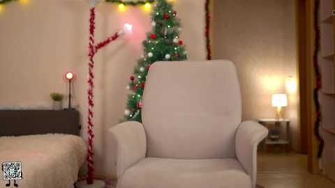 Media: A video of a cozy, festive living room with a cream-colored recliner chair, a decorated Christmas tree, string lights, a fluffy white rug, and a warm, ambient glow.