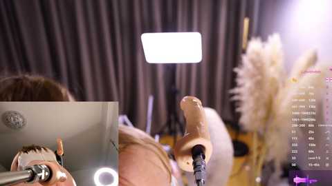 Media: Video of a close-up view of a man holding a camera in front of a studio backdrop with soft lighting and a bright spotlight.