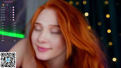 Media: Video of a smiling, fair-skinned woman with vibrant red hair, wearing minimal makeup. She has closed eyes, and the background features blurred, golden bokeh lights. A QR code and streaming app interface is visible in the bottom left corner.